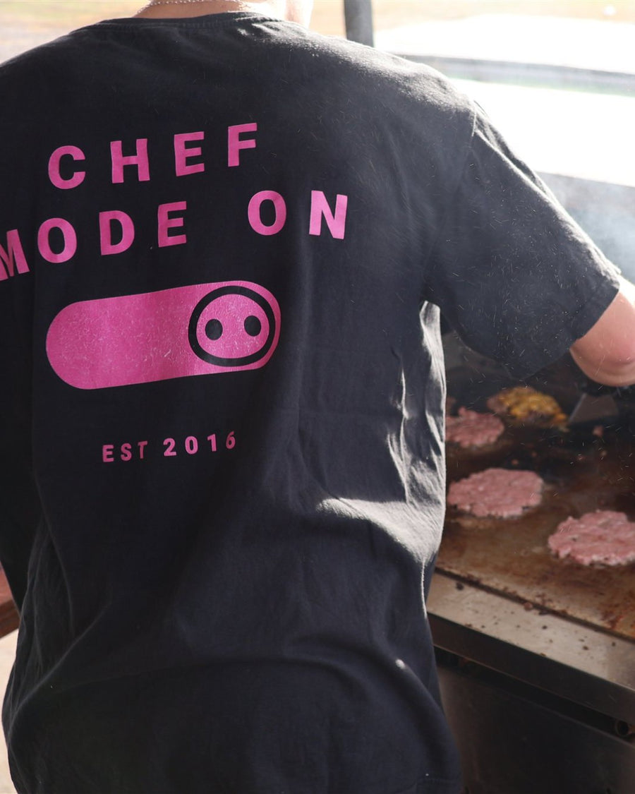 Cocinero con polera Chef Mode On frente a la plancha llena de smash burgers