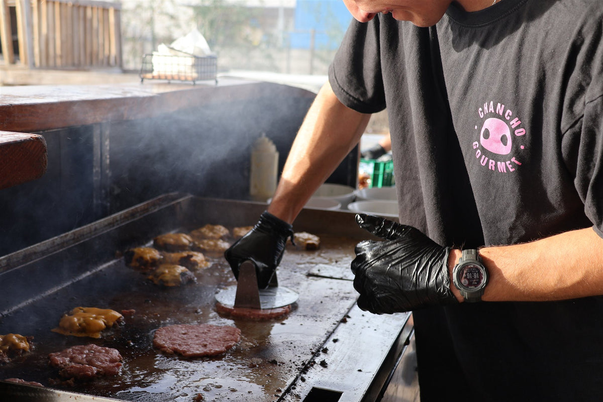 Cocinero de Chancho Gourmet aplastando smash burgers en la plancha del carrito